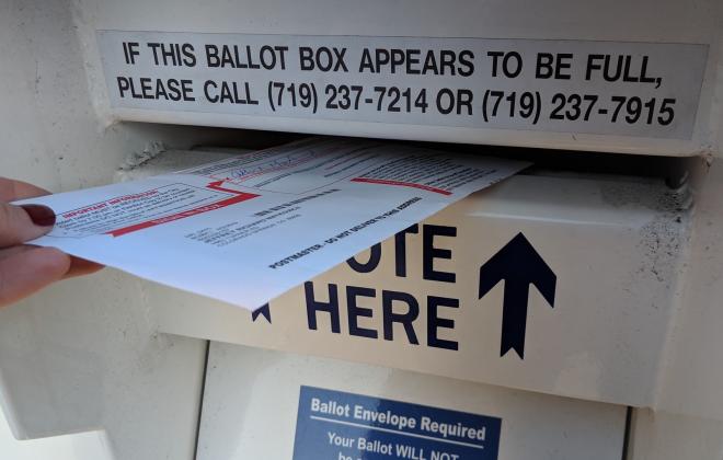 ballot envelope being placed into ballot box