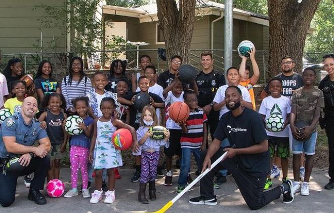 kids holding sport balls pose for photo with officers
